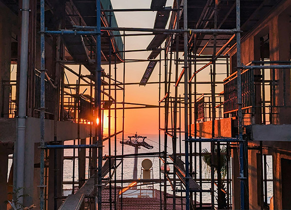 Scaffolding on apartment building and sunset
